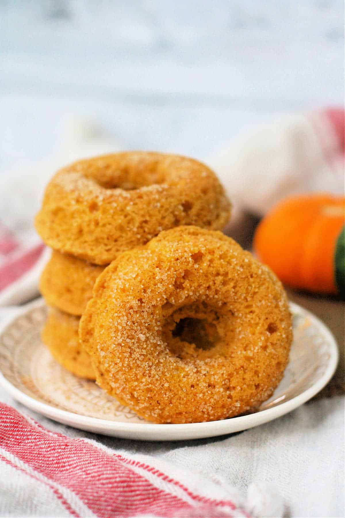 dairy free cinnamon sugar pumpkin donuts stacked on a white plate