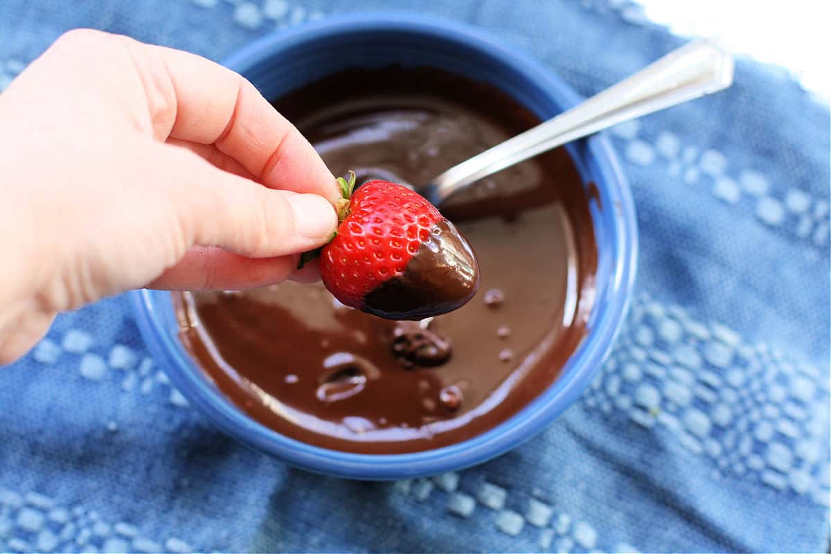 dipping a fresh strawberry in chocolate