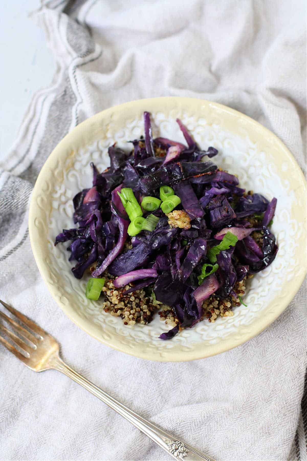 quinoa green onions and red cabbage in a white bowl
