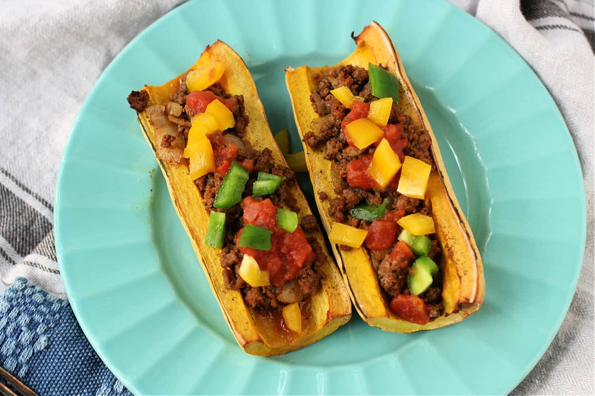 squash taco boats with toppings on an aqua plate