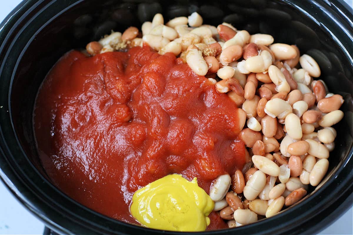 adding the beans ketchup and mustard to the slow cooker