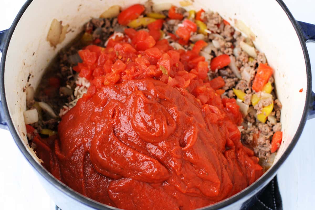 adding tomato sauce and tomatoes to the pot