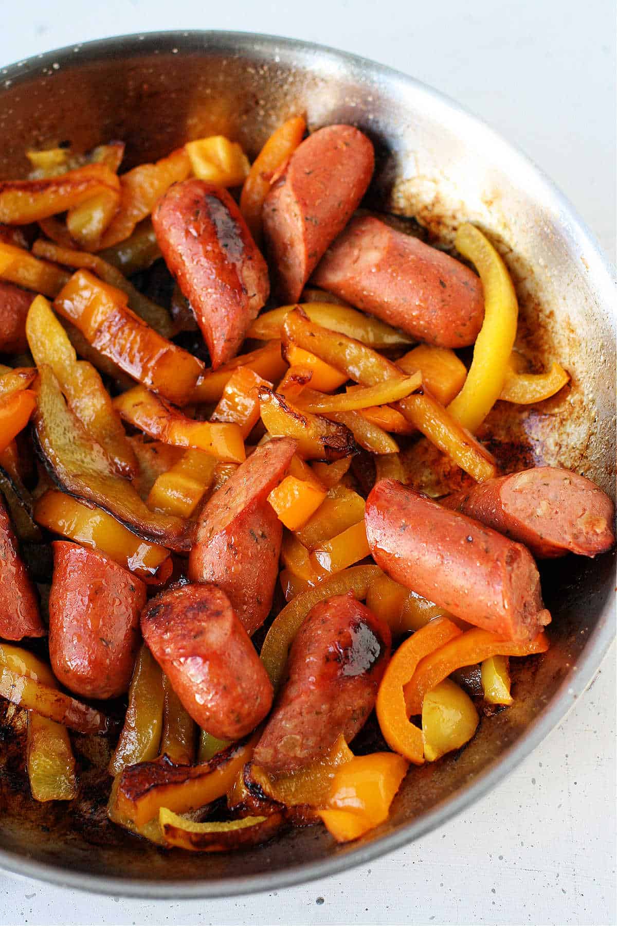 cooking sausages and peppers in a frying pan