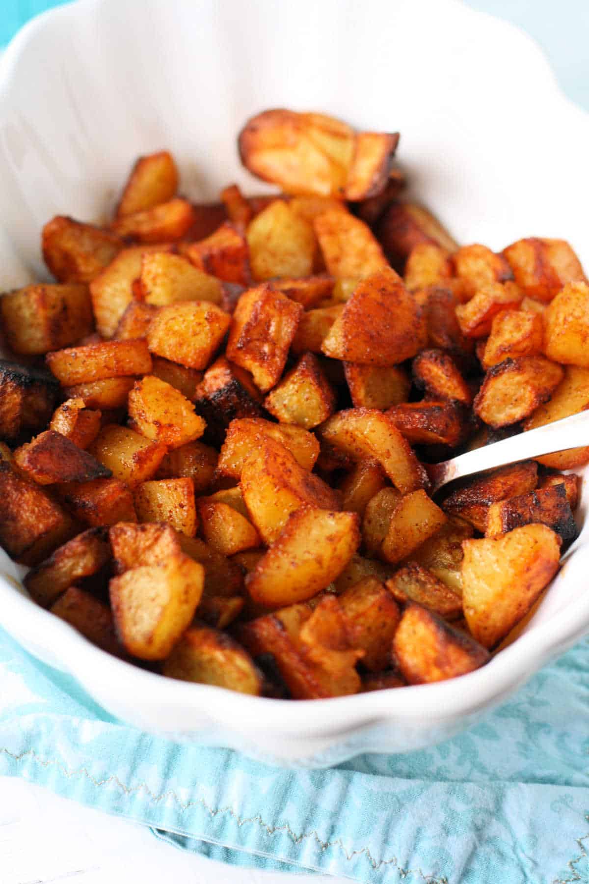 oven roasted potatoes with spices in a white serving dish