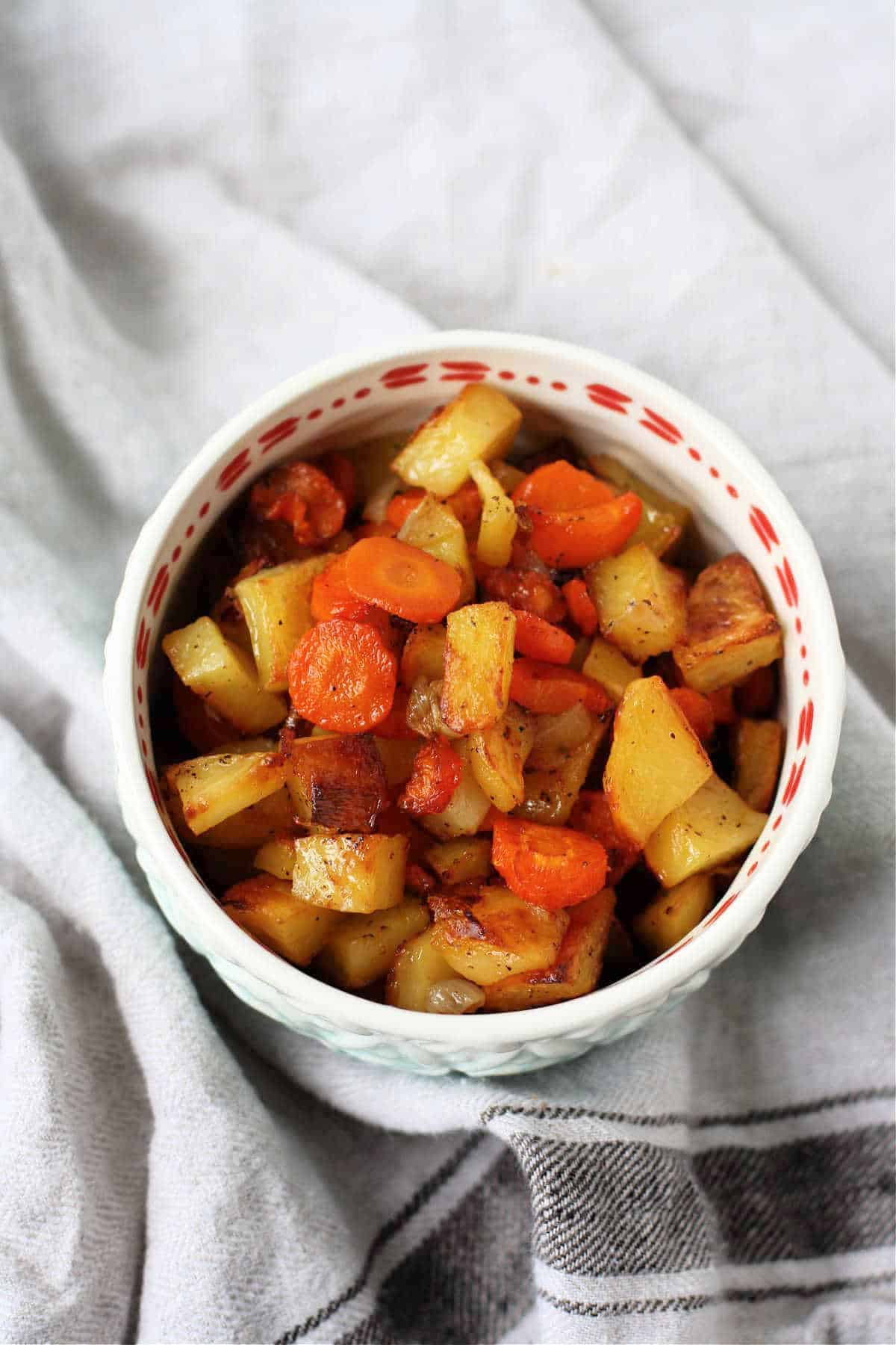 roasted carrots onions potatoes in a white bowl