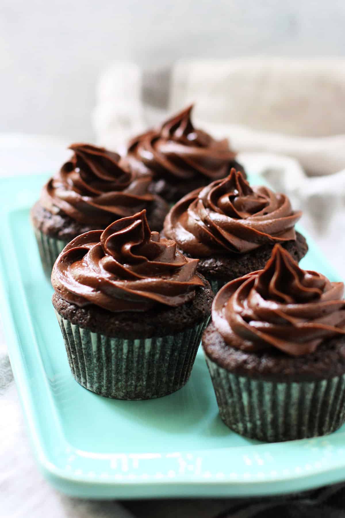 vegan gluten free chocolate cupcakes with chocolate frosting on a teal tray