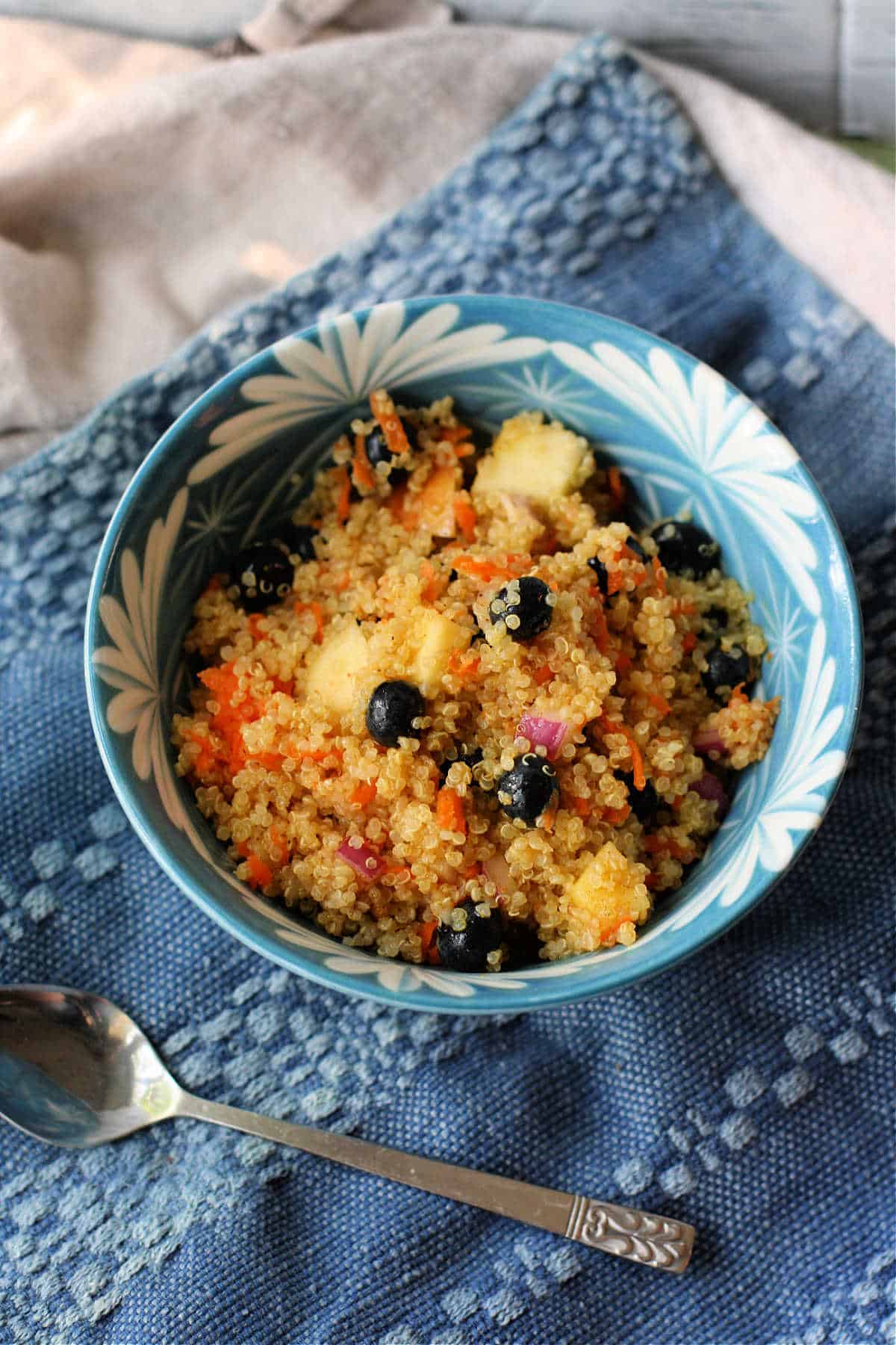 fruit and quinoa salad with curry in a blue and white bowl