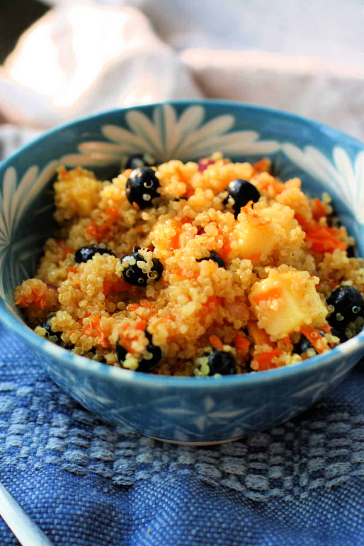 simple curry quinoa salad with fruit in a blue bowl