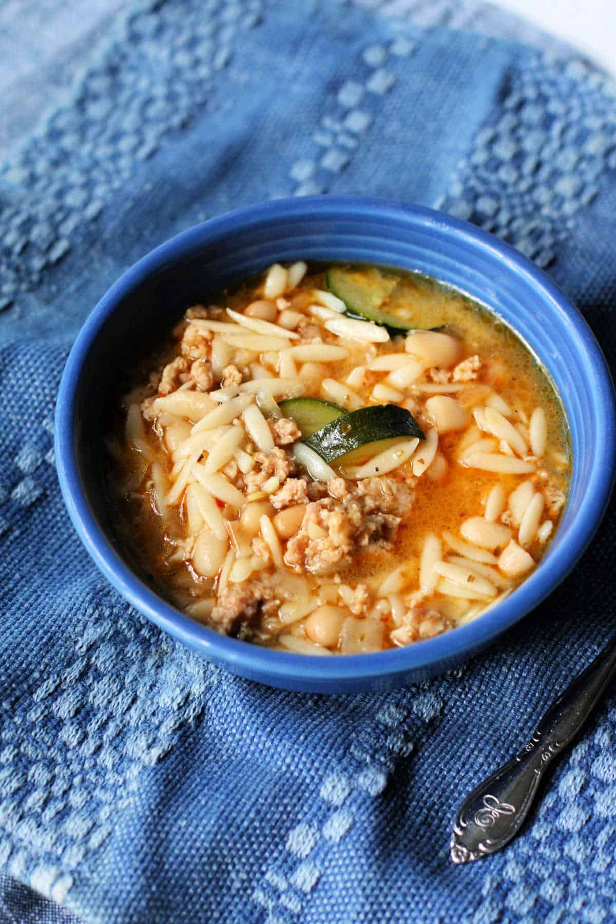 sausage orzo white bean soup in a blue bowl